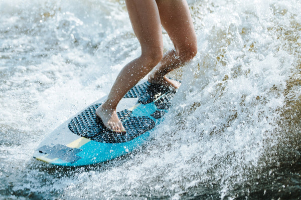 wakesurfer riding a blue and white wakesurf board